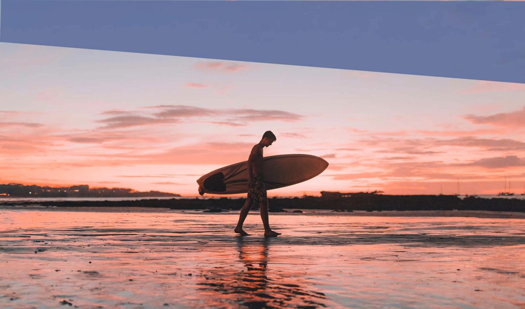 A beautiful community at the heart of all your passions a person carrying a surfboard on the beach